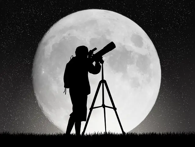 Person using telescope with supermoon background