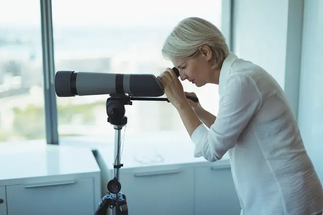 Woman using telescope to look out a window
