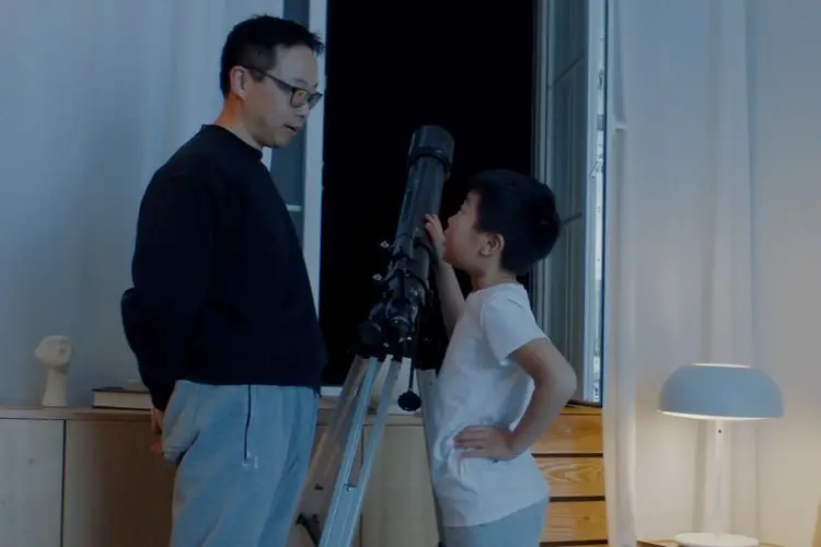 Father and son using telescope at night