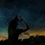 Silhouette of a man stargazing with binoculars